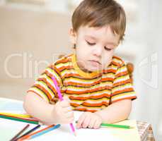 Little boy is drawing on white paper