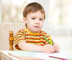 Little boy is drawing on white paper