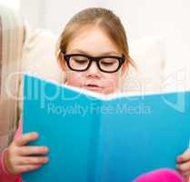 Little girl is reading a book