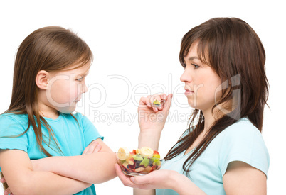 Mother is trying to feed her daughter