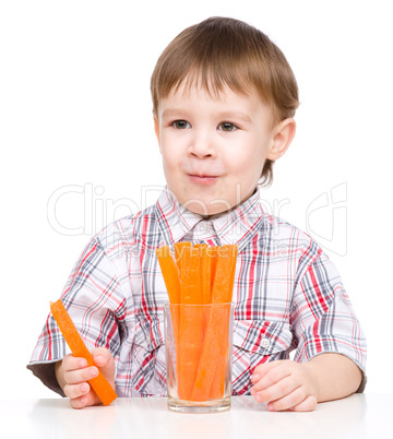 Little boy is eating carrot