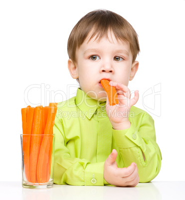 Little boy is eating carrot