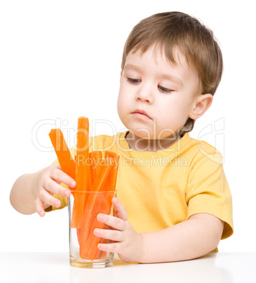 Little boy is eating carrot