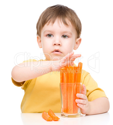 Little boy is eating carrot