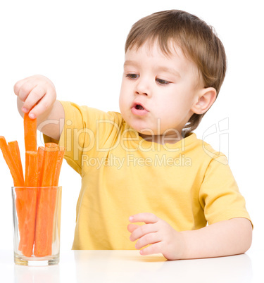 Little boy is eating carrot