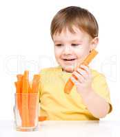 Little boy is eating carrot