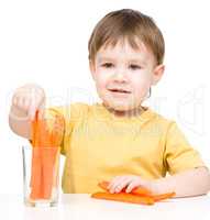 Little boy is eating carrot