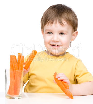 Little boy is eating carrot