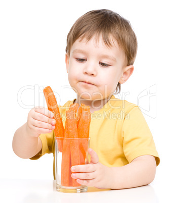 Little boy is eating carrot