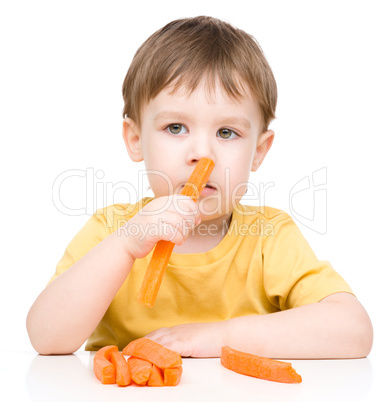 Little boy is eating carrot