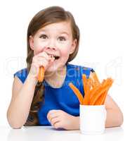 Cute little girl is eating carrot