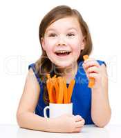 Cute little girl is eating carrot