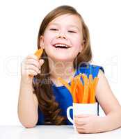 Cute little girl is eating carrot