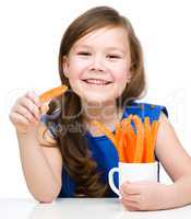 Cute little girl is eating carrot