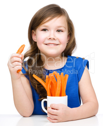 Cute little girl is eating carrot