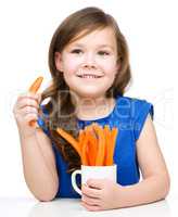 Cute little girl is eating carrot