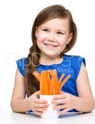 Cute little girl is eating carrot