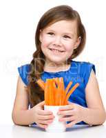 Cute little girl is eating carrot