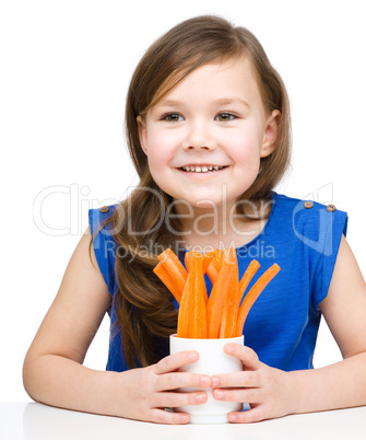 Cute little girl is eating carrot