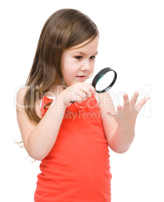 Little girl is looking at her palm using magnifier