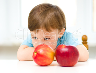 Portrait of a sad little boy with apples