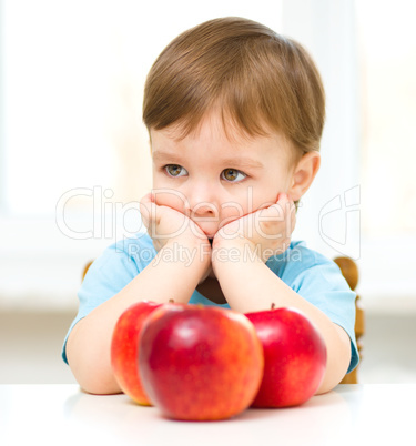 Portrait of a sad little boy with apples
