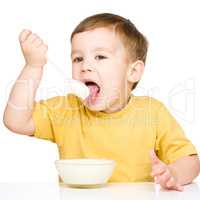 Cute little boy is eating cottage cheese