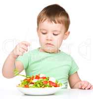 Cute little boy is eating vegetable salad