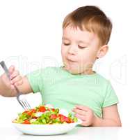 Cute little boy is eating vegetable salad