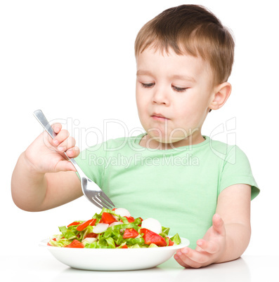 Cute little boy is eating vegetable salad