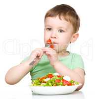 Cute little boy is eating vegetable salad