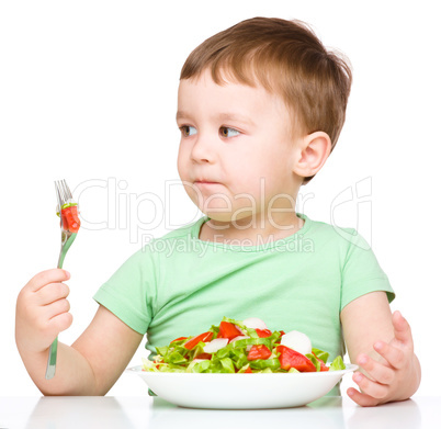 Cute little boy is eating vegetable salad