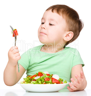 Cute little boy is eating vegetable salad