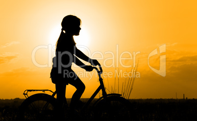 Silhouette of little girl on a bicycle