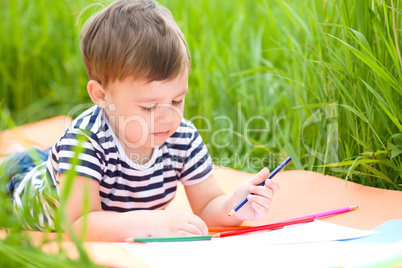 Little boy is playing with pencils