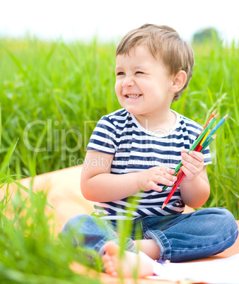 Little boy is playing with pencils