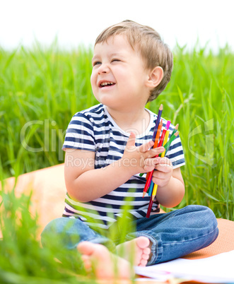 Little boy is playing with pencils