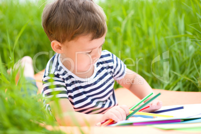 Little boy is playing with pencils