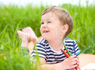 Little boy is playing with pencils