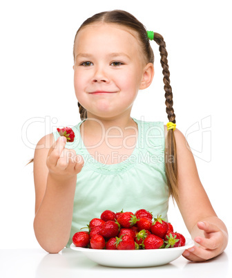 Happy little girl is eating strawberries