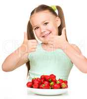 Happy little girl is eating strawberries