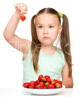 Little girl is eating strawberries