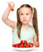 Little girl is eating strawberries