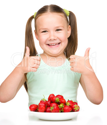 Happy little girl is eating strawberries