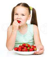 Little girl is eating strawberries