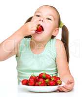 Little girl is eating strawberries