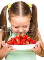 Happy little girl is eating strawberries