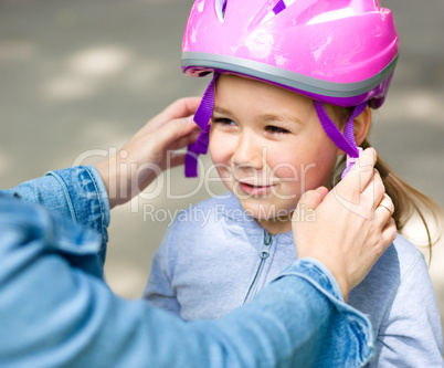 Mother is helping her daughter with safety helmet