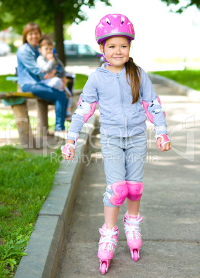Happy little girl is skating on rollers