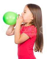 Little girl is inflating green balloon